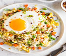 A plate of fried rice topped with a fried egg, showcasing Indian and Nepali cuisine at a premier restaurant.