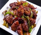 A white plate featuring a vibrant dish of chicken and peppers, showcasing Indian and Nepali culinary excellence.