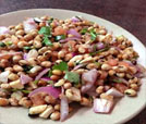 A plate of beans and onions served on a table, showcasing Indian and Nepali cuisine at a premier restaurant.