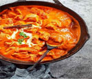 skillet brimming with aromatic chicken curry and spices, showcasing Indian and Nepali culinary excellence.