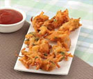 A vibrant plate filled with fried delicacies and a small bowl of ketchup, representing the best of Indian and Nepali flavors.