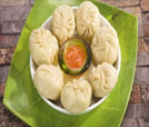 Dumplings served on a plate with a bowl of sauce, highlighting the culinary offerings of an esteemed Indian and Nepali restaurant.