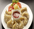 A plate of dumplings served with sauce, showcasing the culinary delights of Indian and Nepali cuisine at a premier restaurant.