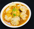 A plate of dumplings served with sauce, showcasing the culinary excellence of Indian and Nepali cuisine at a premier restaurant.