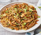 A delicious serving of chicken and noodles in a bowl, accompanied by a fork, highlighting exceptional Indian and Nepali dishes.