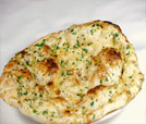 A white plate featuring a bread dish, representing the culinary offerings of an Indian and Nepali restaurant.