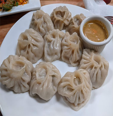 A plate of dumplings accompanied by a flavorful dipping sauce, showcasing Indian and Nepali culinary excellence.