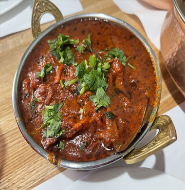 A bowl of curry on a wooden table, showcasing the rich flavors of Indian and Nepali cuisine at a premier restaurant.