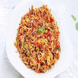 A white plate brimming with colorful noodles and fresh vegetables, showcasing the essence of Indian and Nepali cuisine.