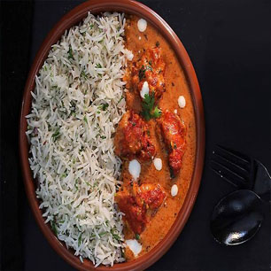 A plate featuring rice accompanied by flavorful chicken curry, representing Indian and Nepali cuisine at a top restaurant.